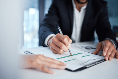 Business professional signing documents during a formal meeting at an office desk.