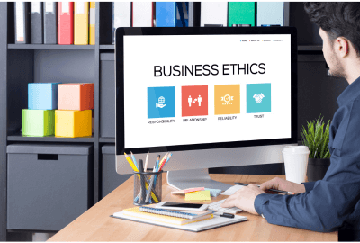 Professional reviewing business ethics concepts on a computer screen in a modern office workspace.