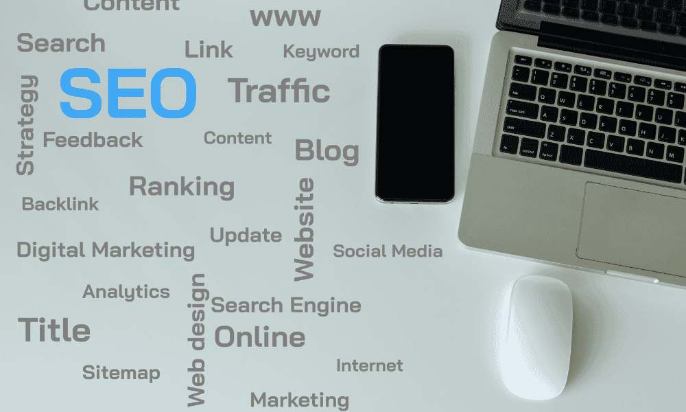 A laptop and smartphone on a desk surrounded by SEO-related words like "Traffic," "Ranking," and "Blog.