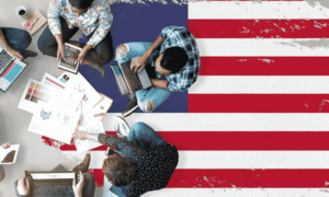 People sitting on the USA flag and working on their laptops, tabs and mobiles as well